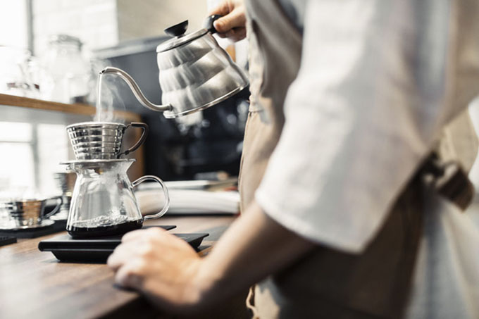 Side view midsection of barista pouring boiling water in coffee